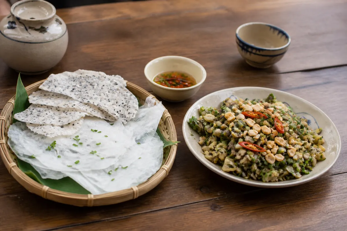 Banh dap rice paper beside chopped clams with herbs, peanuts and chili